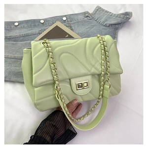 Detail of light green quilted chain bag with gold rectangular metal turn-lock closure