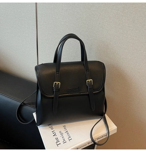 Detail of black PU leather tote bag showing gold buckles and adjustable shoulder strap