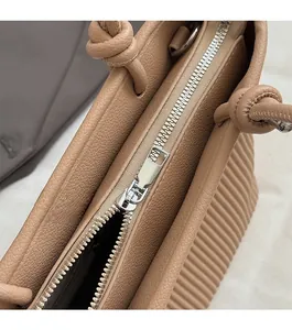 Close-up of smooth zipper closure and knotted leather handle on beige woven texture bucket bag