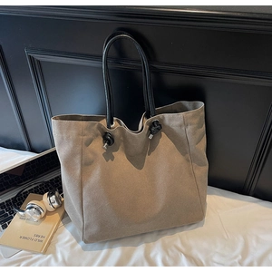 Detailed view of khaki canvas tote bag with black knotted handles and textured fabric