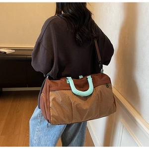 Side view of large checkered travel bag with mint green handles on model's shoulder