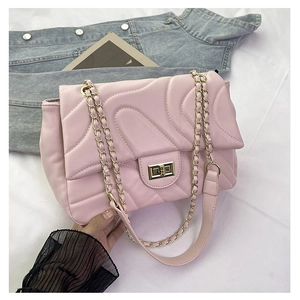 Detailed view of pink quilted handbag with gold twist lock and woven chain strap