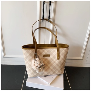 Detail view of large checkered tote bag with brown straps and white bunny charm