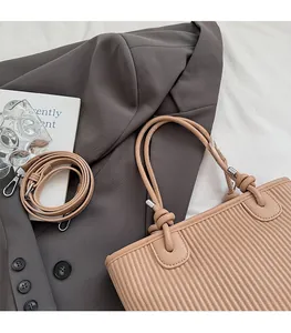 Detail of apricot pleated tote bag showing soft texture with adjustable strap and handles