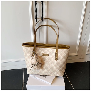 Detail of checkered tote bag with brown leather handles and cute plush bunny charm