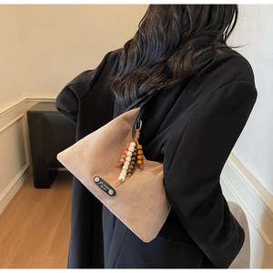 Détail du sac bandoulière en daim marron avec perles en bois colorées et style minimaliste