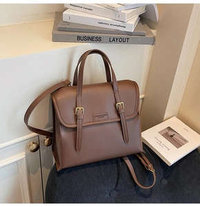 Detail of vintage dark brown leather backpack with gold buckles on a velvet stool