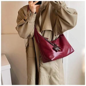 Detailed view of burgundy vintage hobo bag with a cute brown rabbit pendant on a model