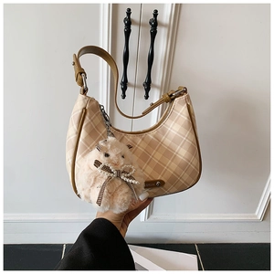 Detail of checkered hobo tote bag with plush animal charm and metal logo plaque