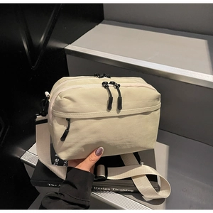 Close-up of canvas crossbody bag with multi-compartment design and double zippers