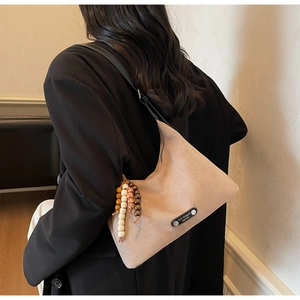 Gros plan détaillé du sac hobo en daim beige avec pampille décorative en perles de bois