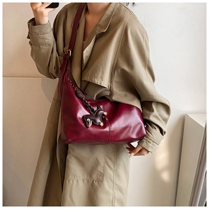 Close-up of burgundy leather bucket bag with gold hardware and horse charm