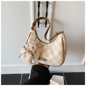Detail of checkered tote bag with brown leather trim and a white plush rabbit pendant