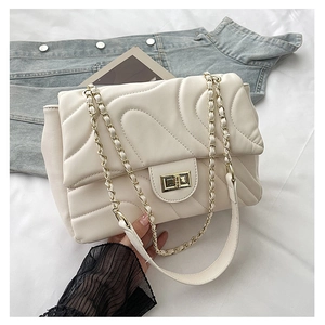 Close-up of cream quilted wave pattern and gold metal twist lock on a shoulder bag