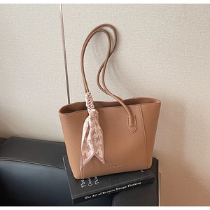 Close-up of brown litchi pattern leather tote bag with a pink houndstooth silk scarf