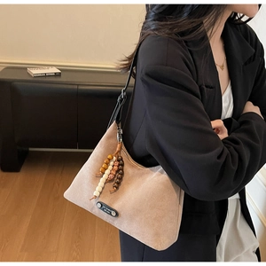 Détail du sac hobo en daim kaki clair avec pompon en perles et sangle en cuir