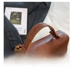 Detail of reinforced leather handle and golden metal buckle on a brown vintage backpack
