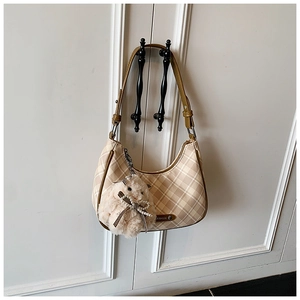 Detailed view of beige plaid pattern texture and cute plush animal charm on tote bag