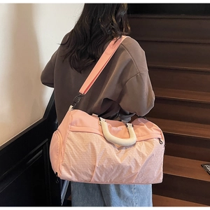 Pink large capacity travel bag with grid pattern shown being carried by a model on stairs