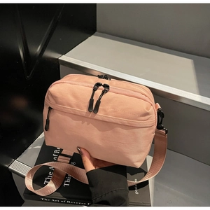 Close-up of pink nylon crossbody bag with dual zippers and wide adjustable strap