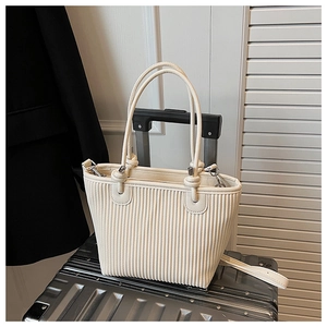 Detail view of the pleated beige tote bag texture and round handles on a suitcase
