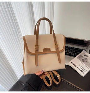 Detail of a beige and brown color-block backpack with golden buckles and logo patch