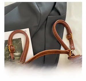 Detail of adjustable shoulder strap with golden metal buckle on retro brown leather bag