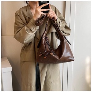 Detail of a brown leather crescent hobo bag with adjustable strap and puppy charm