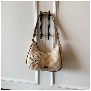 Detail view of beige plaid tote bag with plush rabbit charm on a metal handle