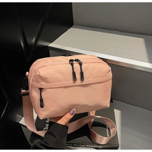 Detail view of pink multi-layered zipper crossbody bag with adjustable wide strap on props