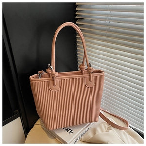 Detail of a pink pleated bucket bag featuring woven textures and decorative knot handles