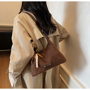 Détail du sac à main marron mat avec breloque bohème en perles et rivets métalliques