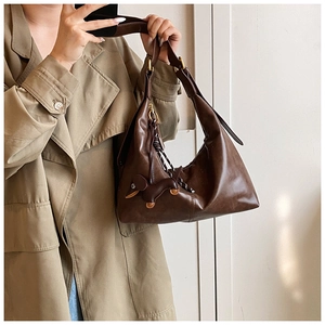 Close-up of vintage brown leather hobo bag with adjustable strap and cute dog charm
