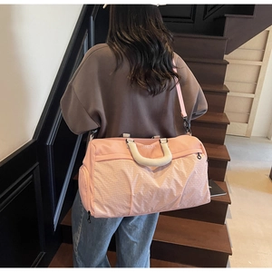 Pink travel bag detail featuring white grid pattern and detachable shoulder strap on model