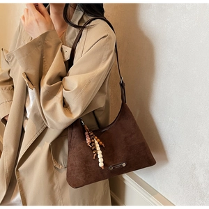 Gros plan du sac hobo en daim marron vintage avec charme en perles ethniques