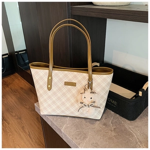 Detail of beige plaid tote bag with brown leather trim and cute plush bunny charm