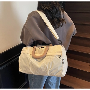 Detail view of cream nylon gym bag with geometric texture and brown shoulder strap