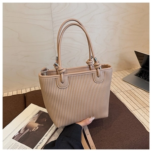 Detail of apricot woven texture handbag featuring elegant vertical pleats and knot handle decor