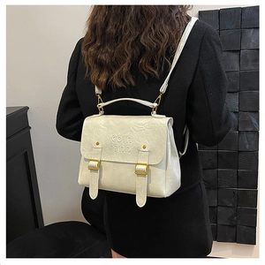 Detail of white PU leather backpack featuring vertical straps and golden metal buckles
