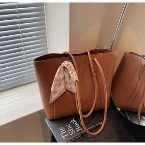 Detail of a brown lychee pattern leather tote bag with a checkered silk scarf decoration