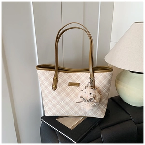Detail of checkered tote bag with leather handles and a plush bunny charm on the side
