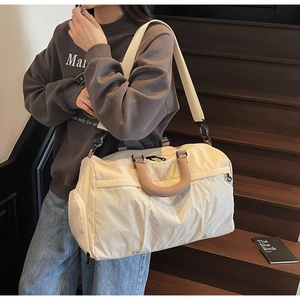 Detail view of large beige travel bag with metal buckles and detachable shoulder strap