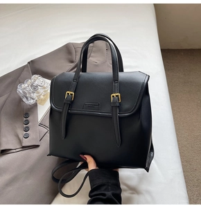 Detail of black leather backpack with gold buckles and embossed fashion logo
