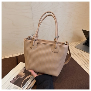 Close-up of beige woven texture bucket bag with knotted handles and silver hardware detail