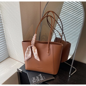 Close-up of brown pebbled leather tote bag with a stylish houndstooth silk scarf detail