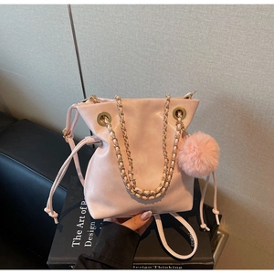 Détail du sac seau en cuir rose avec chaîne dorée et pendentif pompon doux