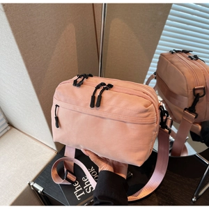 Detail of pink multi-layer crossbody bag featuring wide adjustable strap and zipper pockets
