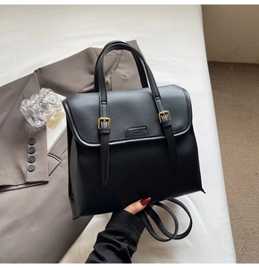 Macro shot of matte black leather bag with gold buckle detailing and embossed fashion text
