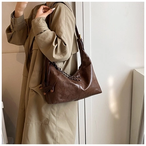 Detail of dark brown crescent shoulder bag with cute dachshund charm and adjustable strap