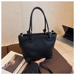 Detail of black pleated crossbody bucket bag with textured vertical stripe design